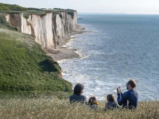 Une famille profitant du panorama sur le sentier du littoral pour faire une pause dans les champs