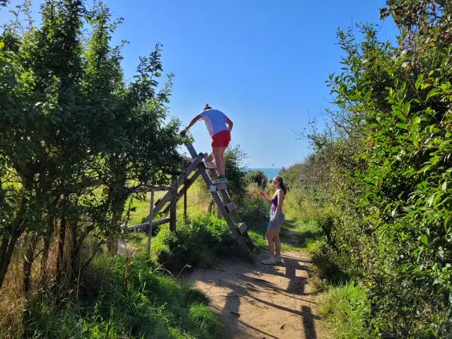 Une famille de randonneur, grimpe sur les passe-clôture du Sentier du Littoral entre Mers-les-Bains et Ault