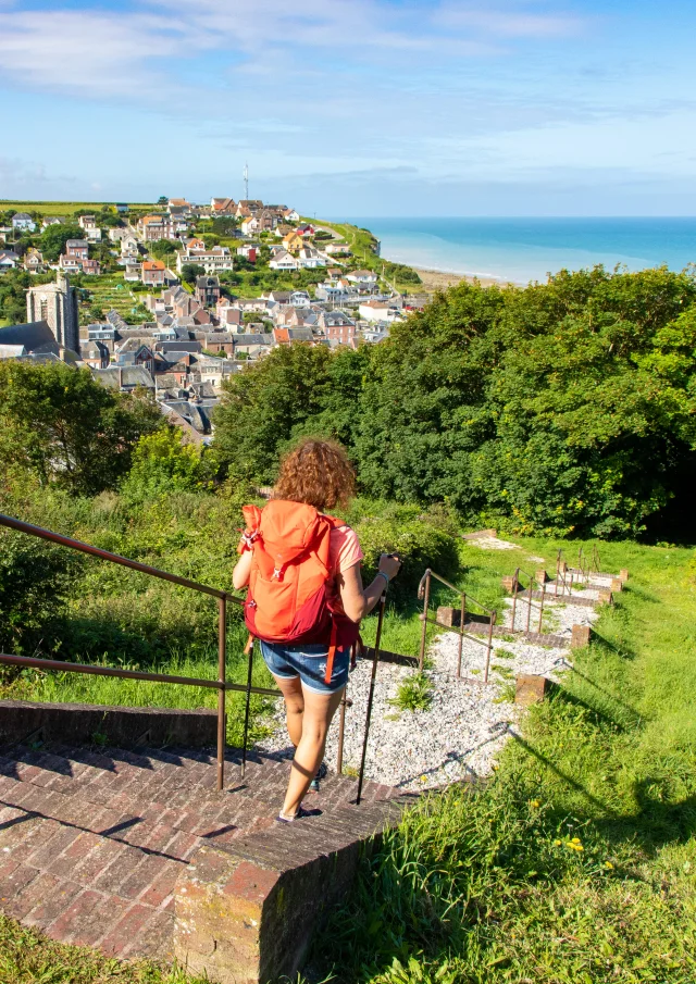 Randonneuse à Ault, descendant les marches de la Porte du Moulinet, profitant du panorama qui d'offre à elle sur le centre-ville et la mer.